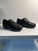 Side view of the black Orthofeet ladies shoe showing the overall design, strap and sole