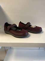Side and top angled view of the burgundy Orthofeet ladies shoes showing design, adjustable strap and sole.