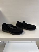 Pair of black Orthofeet ladies shoes showing side angle profile on white surface with neutral background