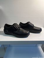 Side view of black Orthofeet ladies shoes showing strap and sole design.