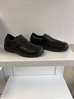Side view of both black leather Orthofeet men's shoes showing design, straps and shape.