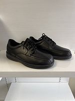 Side angle showing the left and right shoe with lace-up black leather men's shoes.