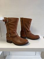 Side view of both brown Steve Madden boots showing the buckled straps and round toe design.