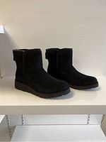 Side angle showing the black suede UGG ladies ankle boots with visible stitching and sole.