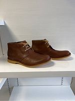 Side view of the pair of brown leather ankle shoes from UGG, showing the outer side of both shoes with crepe rubber soles and laces.