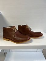 Side view showing the brown leather, lace-up design and rubber sole.