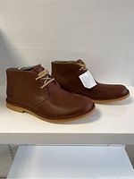 Side view of the pair of brown UGG men's ankle shoes showing the leather finish, tan laces, and stitching around the sole.