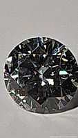 Close-up photo of the 2 carat round brilliant diamond-cut moissanite gemstone showing its facets and brilliance.