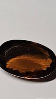 Close-up photo of large faceted oval Madeira citrine with deep cognac color showing facets and light reflections
