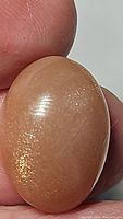 Close-up of oval peach moonstone showing surface texture and shimmer.