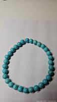 Photo showing a round bead turquoise bracelet laid flat on a white background, displaying the consistent robin's egg blue color of the beads with natural stone variances.