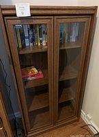 Front view showing wooden bookcase with glass door fronts and books inside