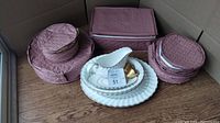 Whole lot of porcelain china plates, bowls, and tea cups in their padded pink storage cases, showing overall quantity and packing.
