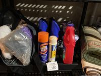Shelf with assorted cleaning spray cans, aerosol cans, and cleaning pads in plastic wrapping
