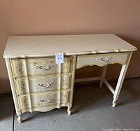 Full view of off-white wooden desk with four drawers and decorative handles