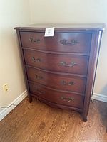 Front view of four drawer tall wooden dresser showing drawer handles and wood finish
