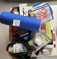 Overhead view of the blue foam roller, collection of exercise books, workout videos, and personal humidifier in packaging.