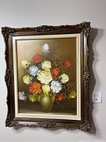 Framed oil painting of a floral rose bouquet with multicolored roses in a green vase, shown hanging on a wall.