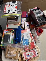 Photo of various playing card decks, boxed card games, cribbage boards, and a mechanical card shuffler