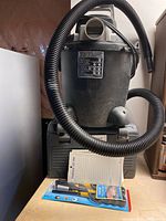 Photo of a black and gray Shop-Vac with hose, a 'Things To Do' notepad and a yellow-handled screwdriver in packaging placed in front.