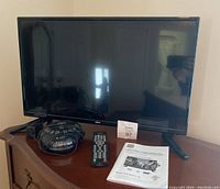 RCA TV/DVD combo with accompanying Conair sound machine, remote, and manual on a wooden surface.