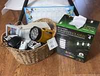 Basket with assorted household accessories including battery chargers, flashlights, solar lights, fridge calendar, computer mouse