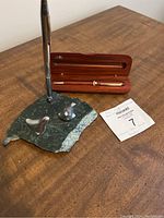 Image showing the vintage marble pen holder with two metallic abstract sculptures and an upright pen, alongside a polished wooden case with collectible pen.