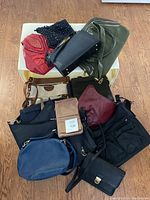 Top view of all ten purses and handbags laid out on a cloth surface showing variety of colors and styles including black, blue, green, burgundy, beige, and beaded.