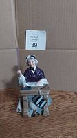 Frontal view of the Royal Doulton teacher figurine seated at the desk, showing detailed facial expression and attire.
