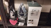 Shelf with both irons and the boxed sewing machine
