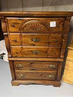 Front view of tallboy dresser showing five drawers with mixed metal handles and carved front detail on top drawer.