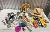 Full view of the kitchen utensils, cutting boards, strainers, and other tools arranged on table showing variety of items
