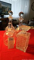 Four clear glass decanters on red fabric, showing overall lot contents and shapes