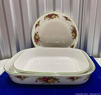 Photo of the set of one round serving bowl and two rectangular serving dishes stacked together showing floral pattern and green rim detail.