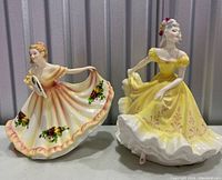 Both Royal Doulton porcelain figurines together on table showing dresses and poses.