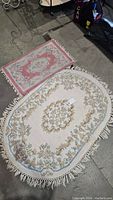 Photo showing both the oval and smaller rectangular wool rugs on a floor with other items in background.