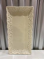 Rectangular ceramic tray with pierced floral border photographed standing upright.