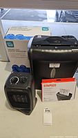 Photo showing the compact Comfort Zone ceramic heater with front mesh and control knobs alongside Pen Gear paper shredder with lubricant sheets and box.