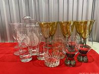 Group photo showing all glasses and pitcher together on a red cloth, highlighting colors and designs of items.