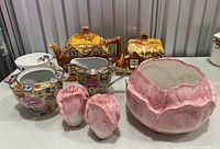 Cottage style china teapot, matching butter dish alongside pink ceramic bowl, cream and sugar bowl, and salt and pepper shakers arranged on table