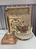 Photo of the entire lot showing floral teapot, paper towel holder, wooden sign, pink glass butter dish, ceramic lattice bowl, and the tray.