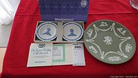 Two Wedgwood Royal Wedding Collection 1981 plates in a blue Wedgwood box with original certificate and a larger green jasperware plate on a red cloth background
