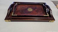 Set of stacked wooden trays showing dark wood and brass hardware