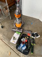 Dyson DC25 Ball vacuum with multiple iRobot Roomba accessories and parts arranged on floor.