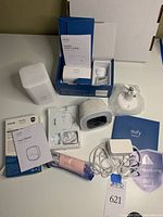 Overview of all items unboxed showing camera, home base, packaging, user guides, mounts, and cables