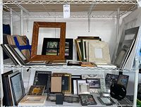 Shelves with various picture frames and mats in multiple sizes and materials including wood, metal, and decorative styles.