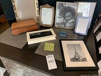 Overview of all items on table including varied picture frames in different sizes and decorative boxes