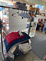 Photo showing portable garment rack loaded with hangers and plush bathmats along with laundry basket