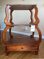 Front view of wooden accent table with curved supports and drawer closed