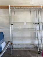 Front view showing full shelving unit with five wire shelves on casters against wall